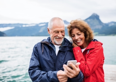 Couple in front of mountains and lake looking at their phone